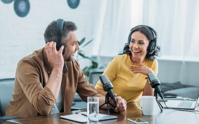 Beschreibung: Ein Mann und eine Frau im Tonstudio mit Mikrofonen und Kopfhörern.