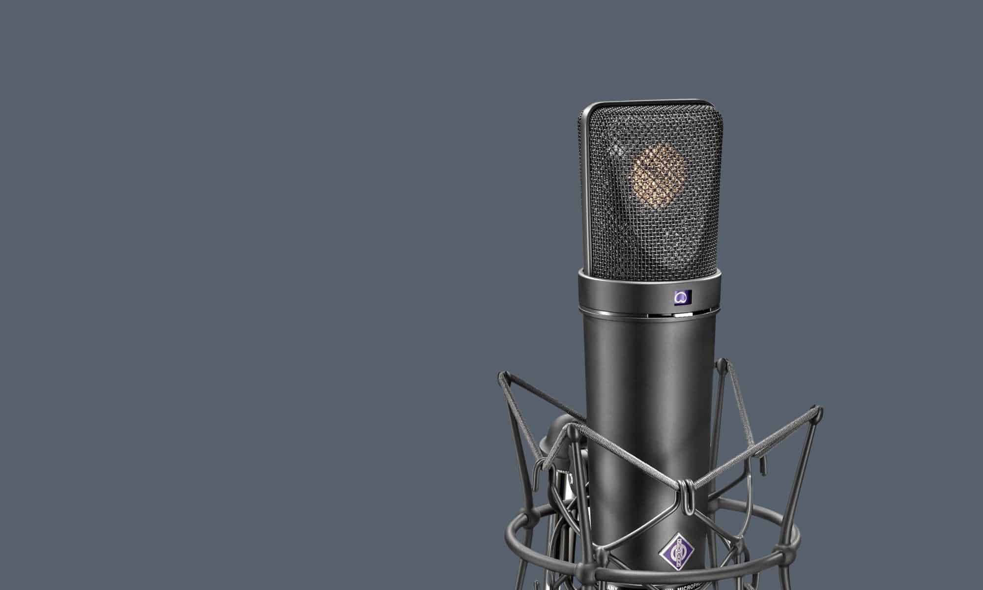 Ein Neumann U87 Mikrofon in einer Mikrofonspinne auf grauem Hintergrund in einem Tonstudio.